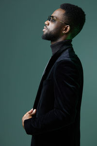 Side view of man standing against gray background