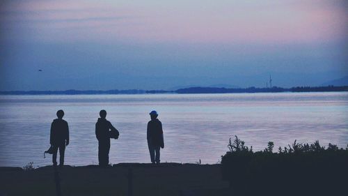 Rear view of silhouette people looking at sea against sky