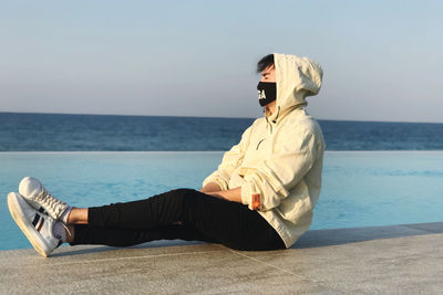 Man sitting in sea against sky