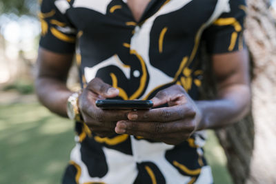 Hands of young man using phone in public park