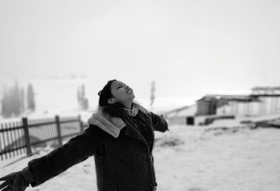 Portrait of young woman standing on beach against sky