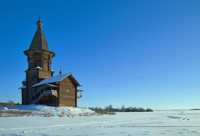 Church by building against clear blue sky during winter