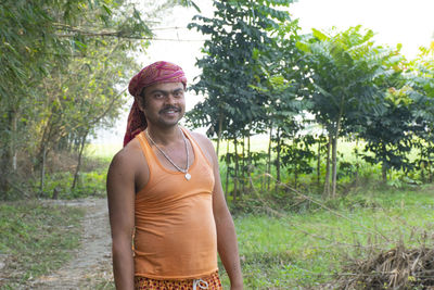 Portrait of young farmer standing against trees