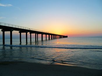 Pier over sea against clear sky during sunset