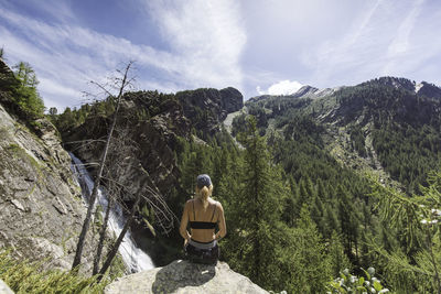 Rear view of man on rock against sky