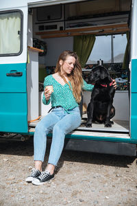 Woman sitting with dog in camper van