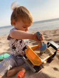Close-up of cute baby boy playing with toy and sand at beach