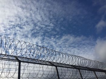 Low angle view of barbed wire fence against sky