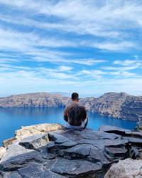 Rear view of shirtless man sitting on mountain