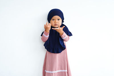 Portrait of cute girl standing against white background