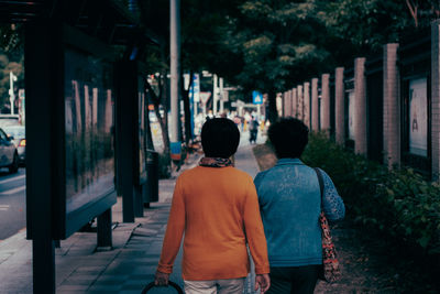 Rear view of people walking on footpath