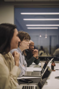 Ambitious female and male colleagues with laptops on desk at office