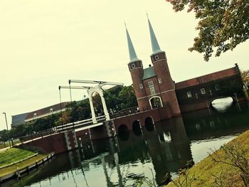 Bridge over river by buildings against sky