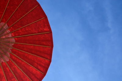Low angle view of red umbrella against blue sky