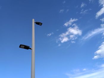 Low angle view of street light against blue sky