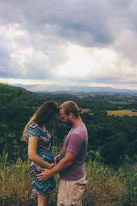 Man standing on field against cloudy sky