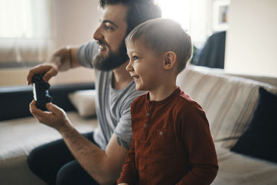 Happy little boy playing computer game with his father at home
