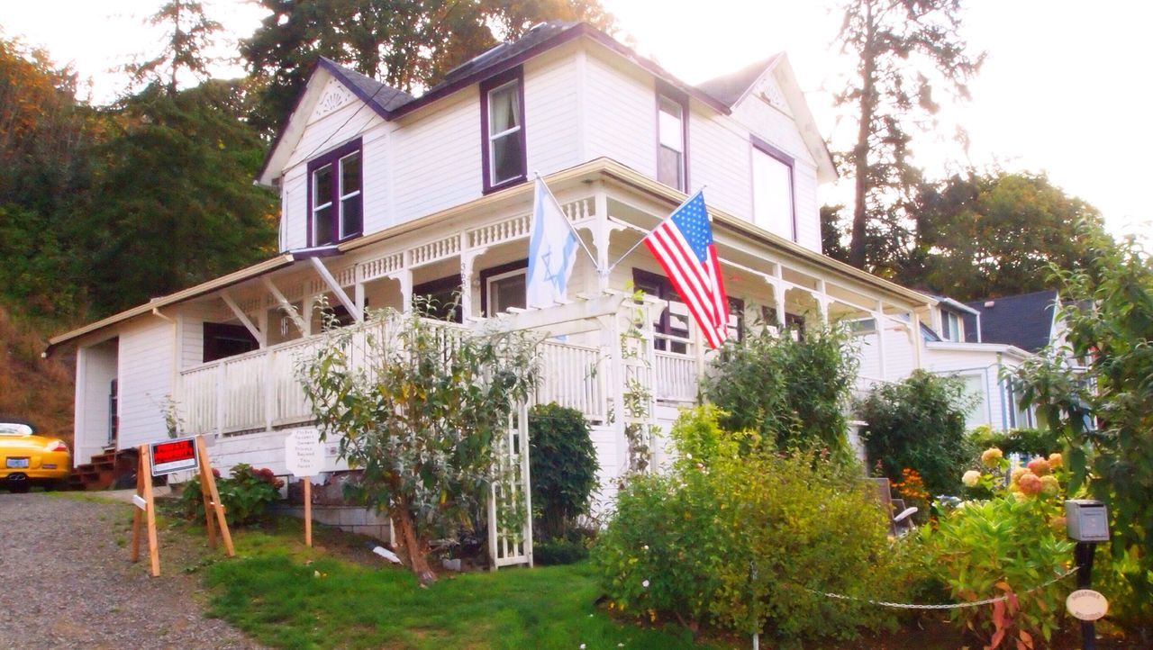 architecture, building exterior, built structure, tree, house, residential structure, residential building, flag, building, day, city, clear sky, outdoors, no people, window, sky, sunlight, patriotism, exterior, multi colored