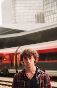 Portrait of young man standing against train