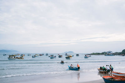 People sailing on sea against sky