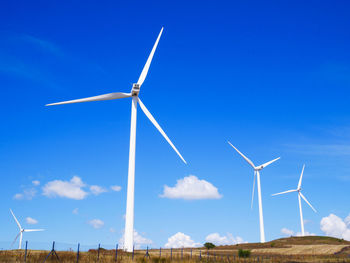 Low angle view of wind turbines on land