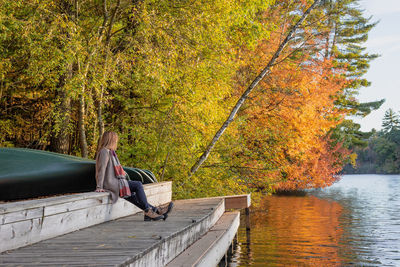 Woman sitting by lake during autumn
