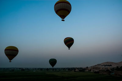 Hot air balloon flying over landscape against blue sky