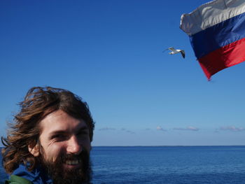 Portrait of man by russian flag against sea