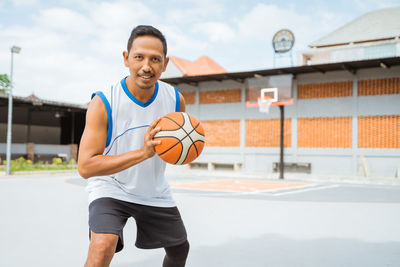 Portrait of man playing with basketball