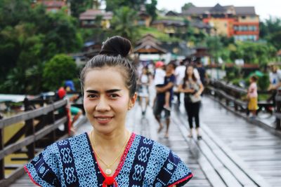 Portrait of smiling woman on footbridge in city