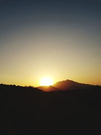 Scenic view of silhouette mountains against clear sky during sunset