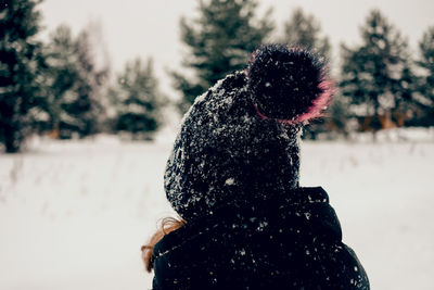 Kid in hat standing rear view  snowy season lifestyle outside