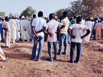 Rear view of people standing on road against sky