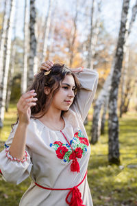 Beautiful woman in national ukrainian national traditional costume clothes walking in forest