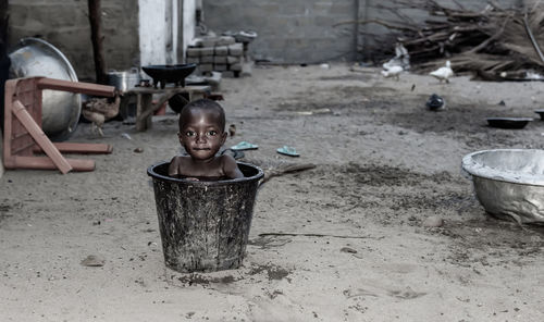 African child cools down in a bucket of water during a hot afternoon ghana west africa.