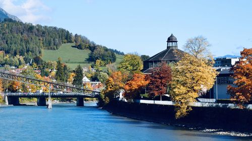 Bridge over river by buildings against sky during autumn