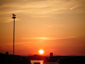 Silhouette street lights against orange sky
