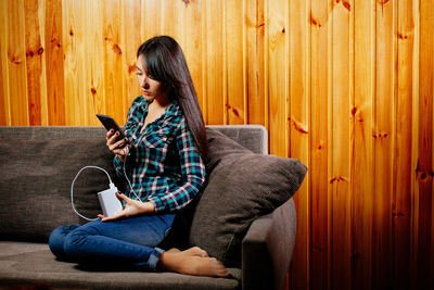 Young woman using phone on sofa at home