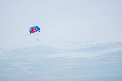 Low angle view of person paragliding against sky