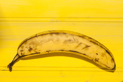 Close-up of banana agains yellow wooden surface