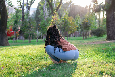 Young european woman is sitting on a grass and doing yoga exercise. healthy lifestyle outdoors.