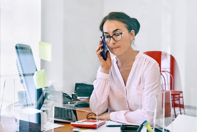 Middle-aged woman social worker check accounts bills, using smartphone to communicate with team