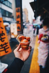 Midsection of woman holding ice cream in city