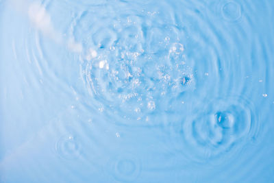 Pouring and splashing clear water on light blue background upper close view