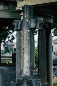 Close-up of cross in cemetery against building