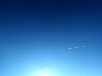 Low angle view of vapor trail against clear blue sky