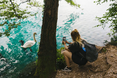 Woman using mobile phone by lake