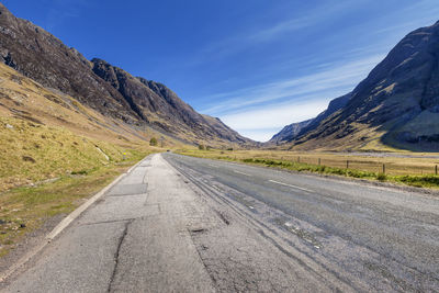 Empty road amidst mountains against sky