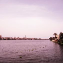 Scenic view of river by buildings against sky