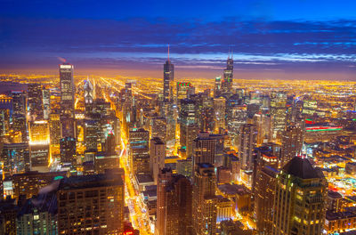 Illuminated cityscape against dramatic sky